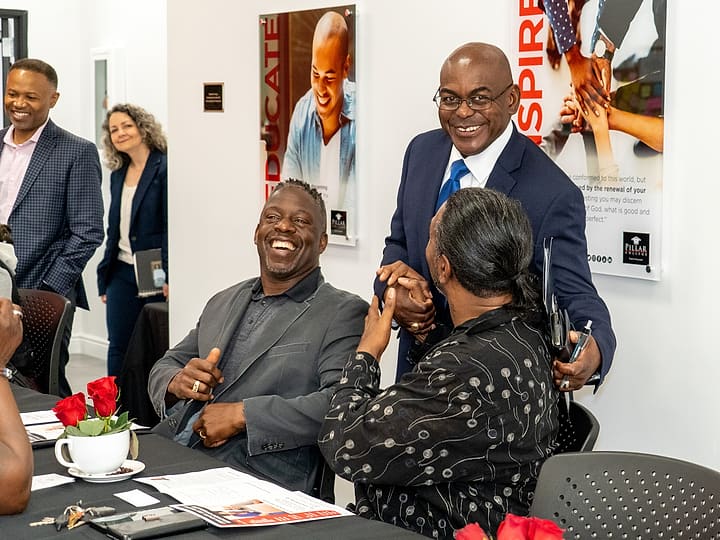 Dr. Rupert A. Hayles Jr. laughing with two participants at a table