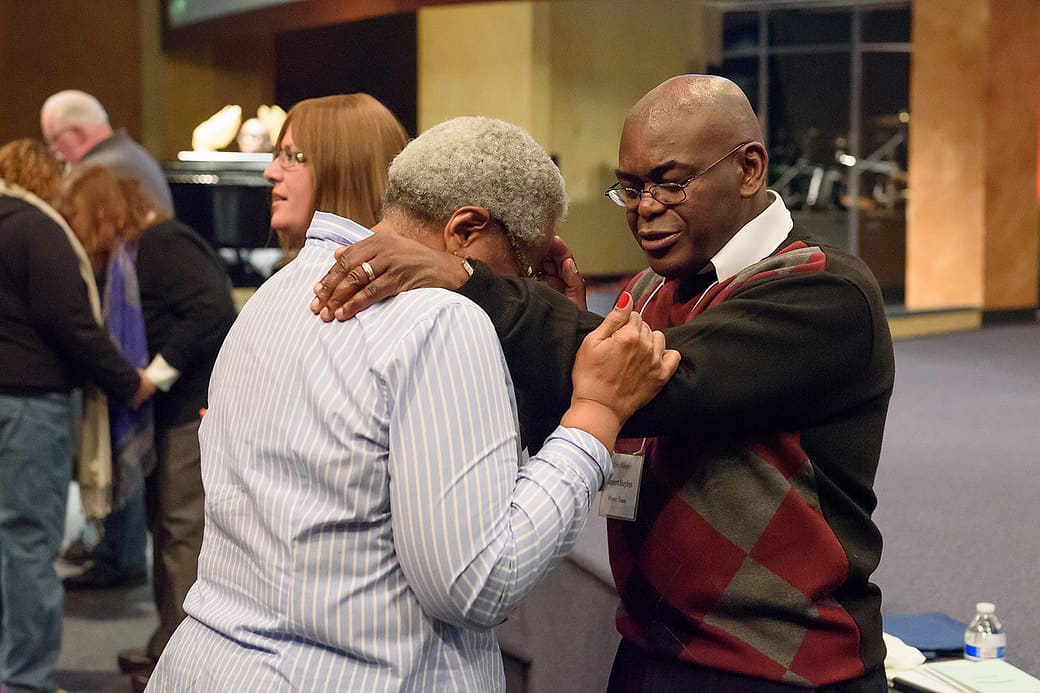 Dr. Rupert A. Hayles Jr. praying with a participant